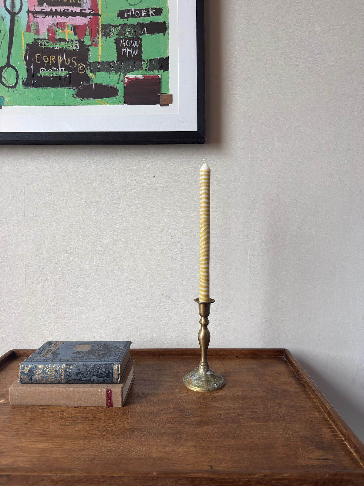 Piccalilli sculptural dinner candle by Pygmalion London in a brass candlestick on a wooden side table