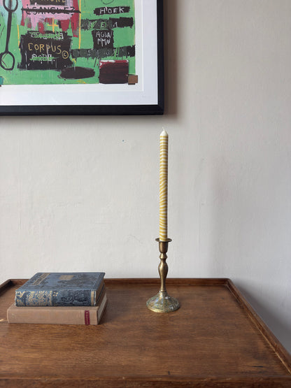 Piccalilli sculptural dinner candle by Pygmalion London in a brass candlestick on a wooden side table