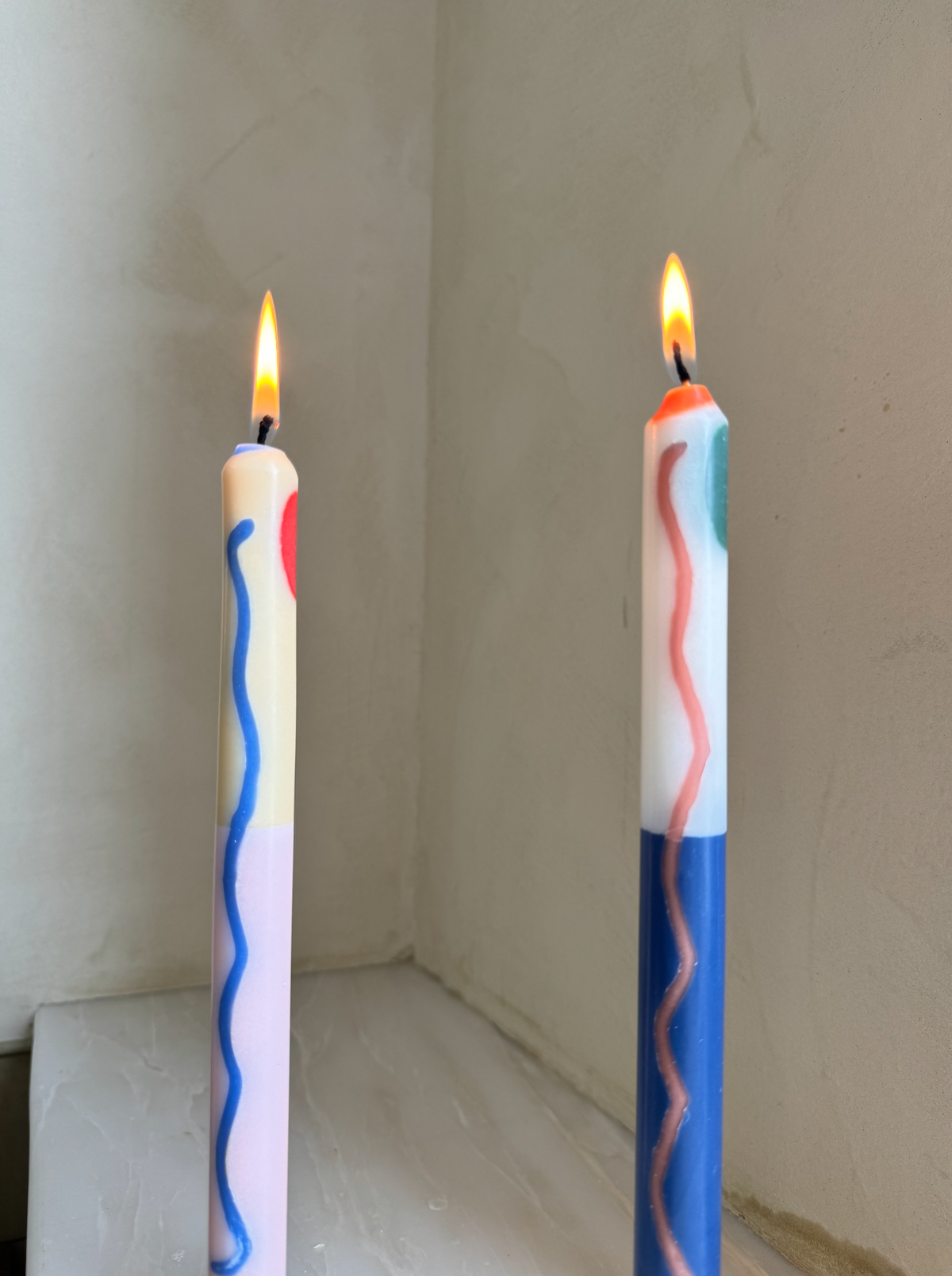 Terracotta patterned dinner candles by Pygmalion London, a hand-poured pair in blue, burnt orange, ochre, mustard yellow, racing green and red