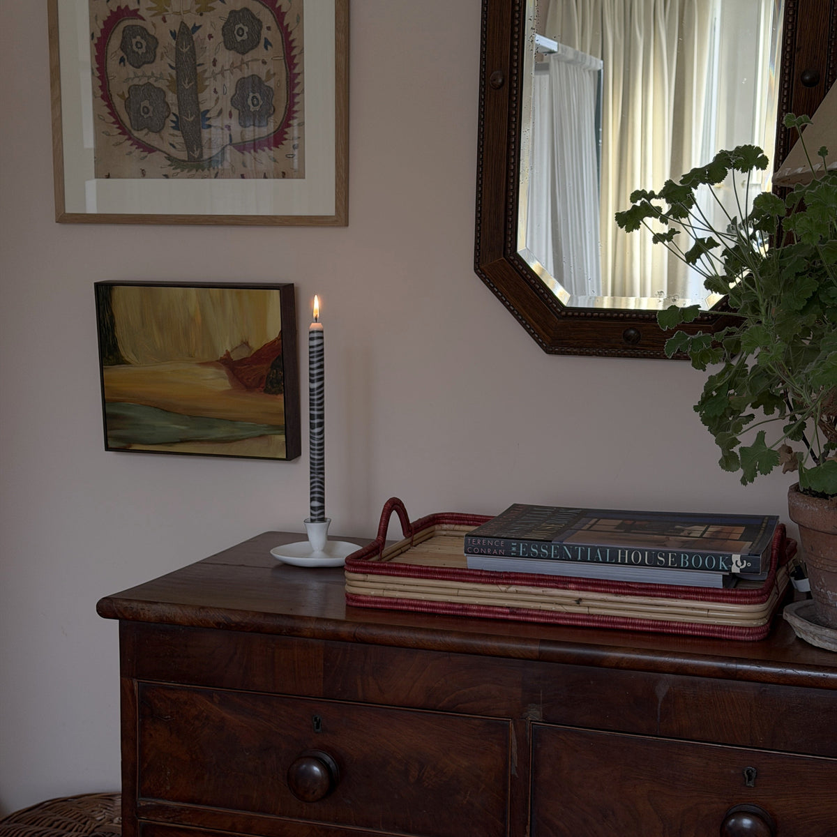Shilling sculptural dinner candle by Pygmalion London, lit on an antique chest of drawers