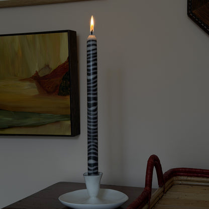 Shilling sculptural dinner candle by Pygmalion London, lit in a white candlestick
