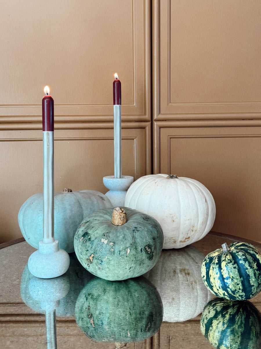 Lit Bramble dinner candles with green and white pumpkins on a mirrored table.