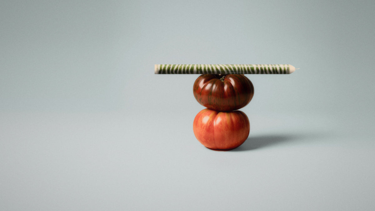 A striped Pygmalion dinner candle balanced on two heirloom tomatoes